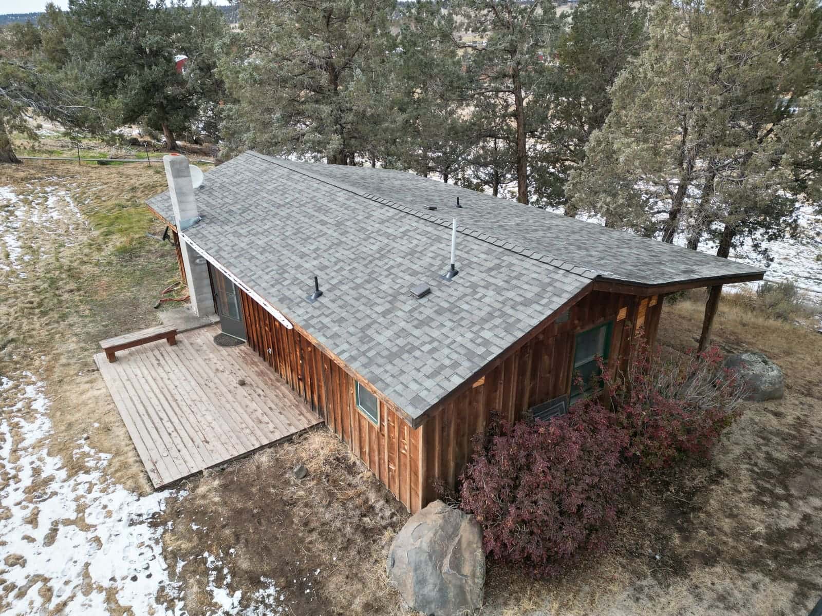 Gray architectural shingles on a small La Pine cabin with a block chimney, snow on the ground