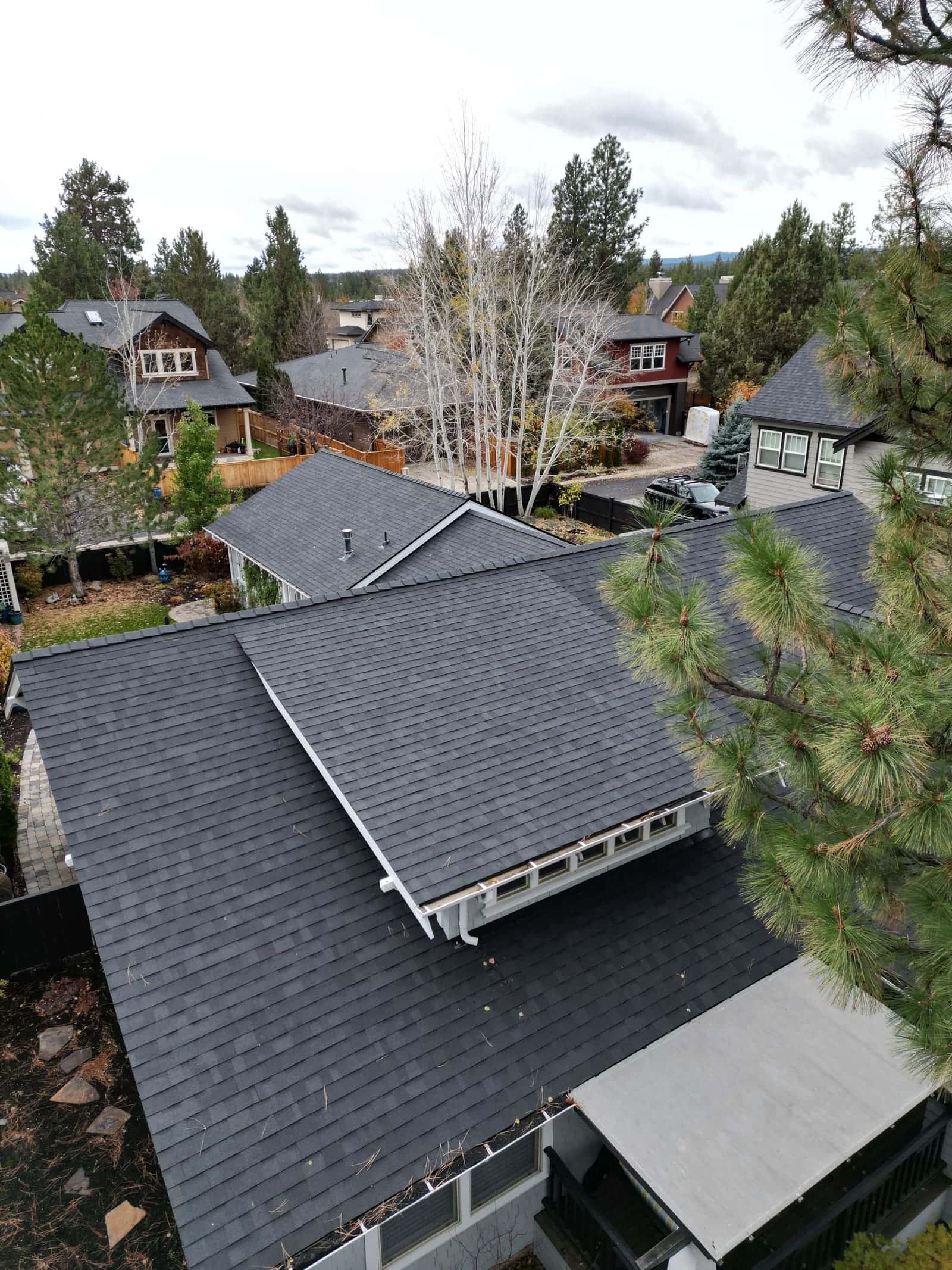 Dark gray architectural shingles on a Redmond home with a dormer, aspens behind