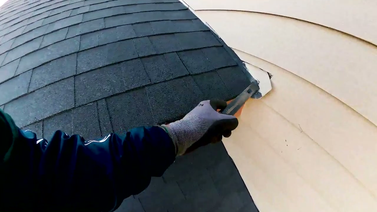 An inspector points to kickout flashing at the lower end of a roof-to-wall connection.