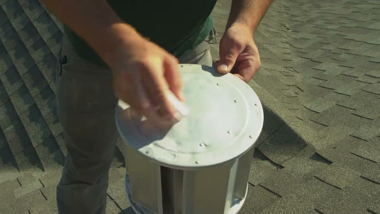 A Greenlee roofer points to small dents on a metal roof vent cap.