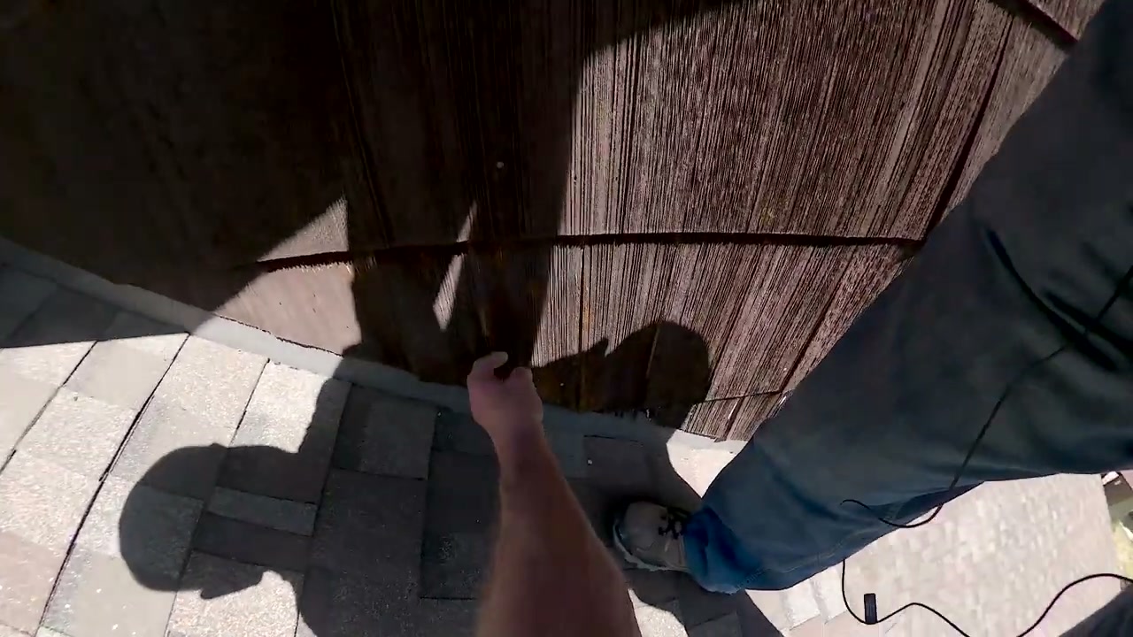 An inspector checks the flashing where shingles meet wood siding.